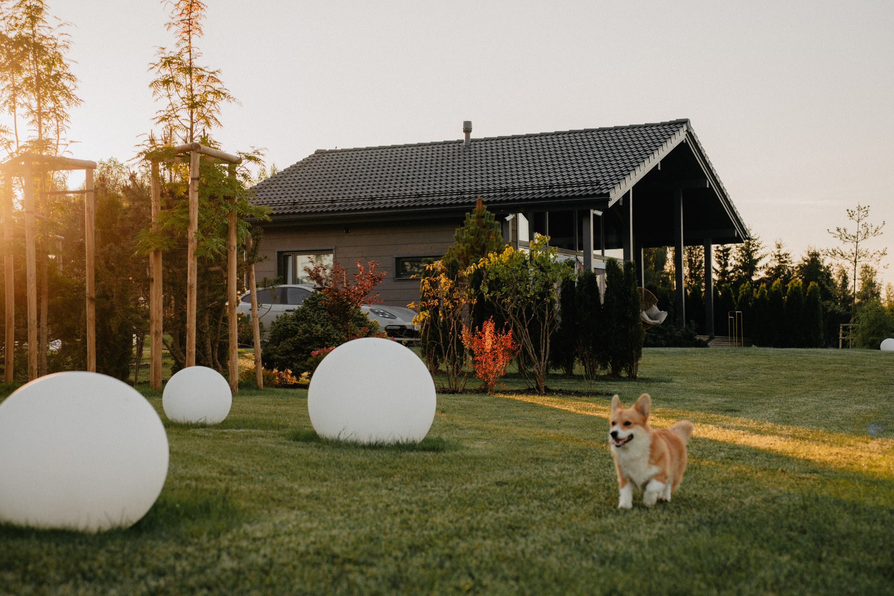 Exterior of a SeoVillage villa with garden spheres and a dog on the lawn